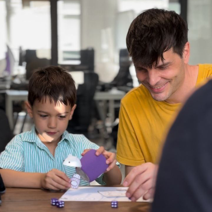 A boy tests the educational games with a TukToro paper figure and the TukToro haptic toy, a smiling adult plays along.