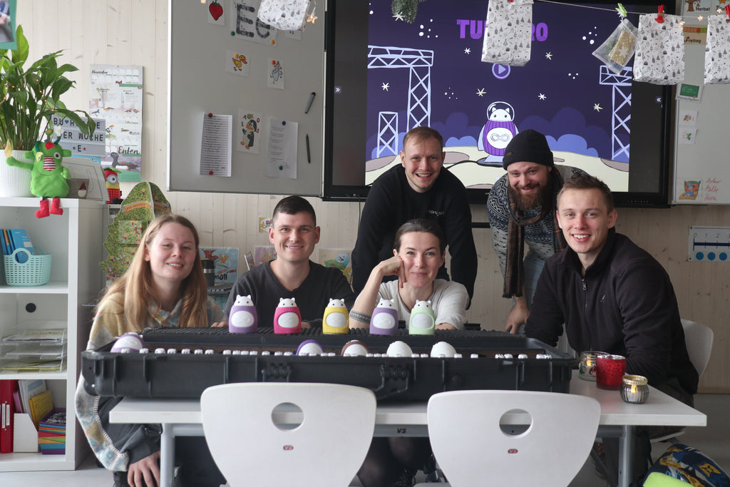 The TukToro team in the classroom with lots of colorful TukToro figures: Annabell Terrahe, Andreas Häring, Justyna Zubrycka, Martin Klemann, Patrick Goehl, Elisha Benner.